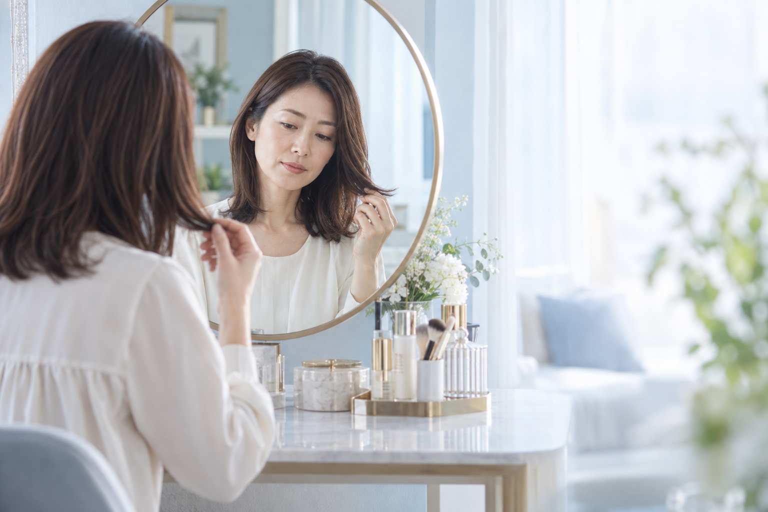 鏡を見ながら毛先の手触りを確かめる女性
